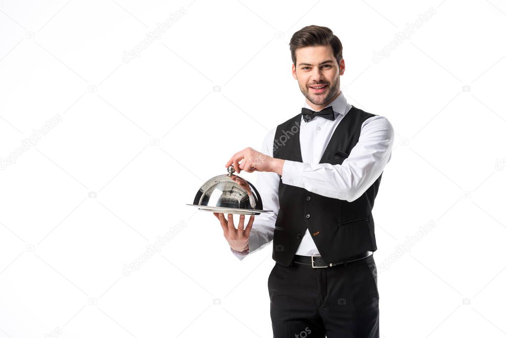 portrait of handsome smiling waiter in suit vest with serving tray isolated on white