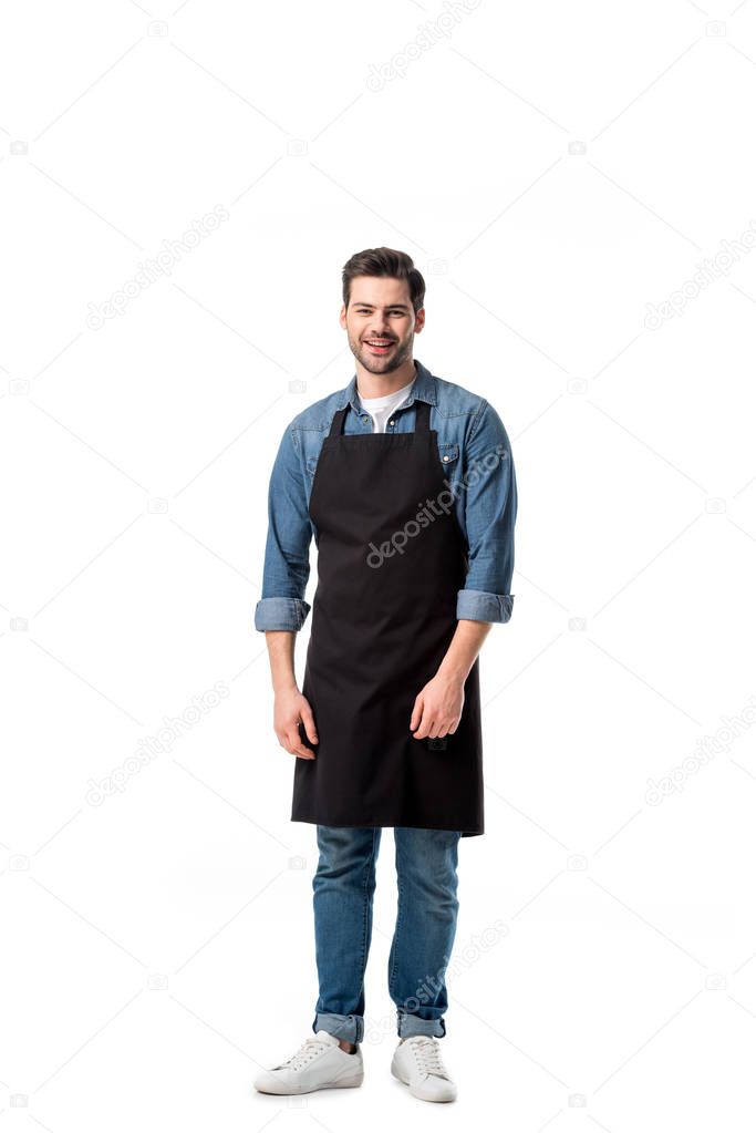 young smiling waiter in apron looking at camera isolated on white