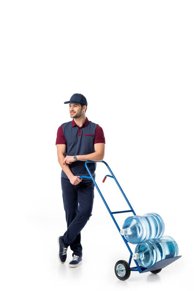 smiling delivery man with large bottles of water on hand truck isolated on white 