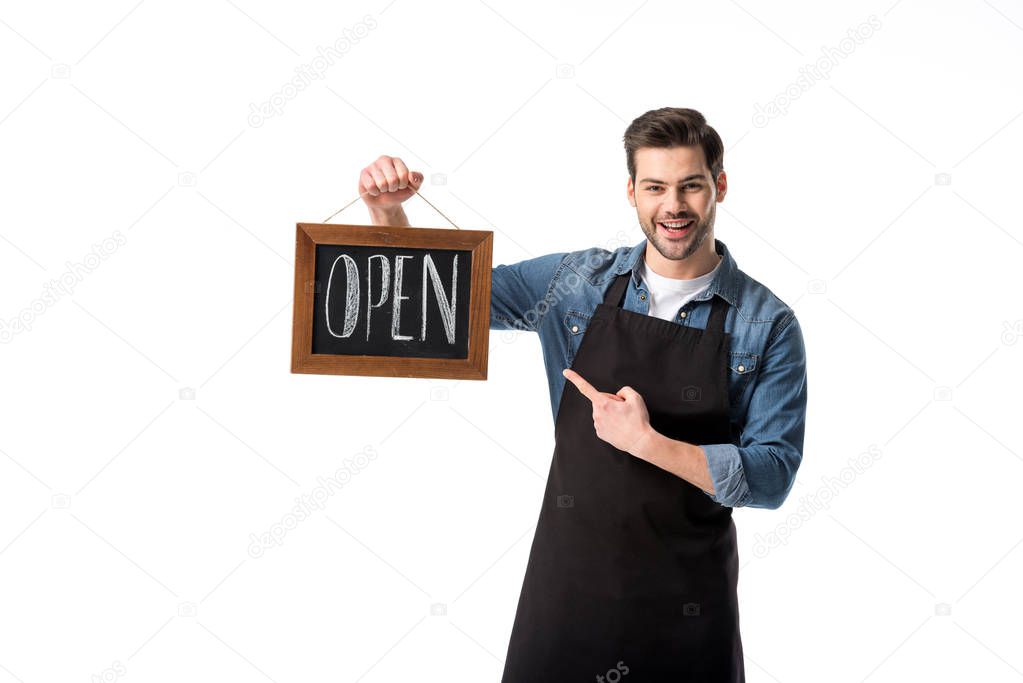 portrait of smiling waiter pointing at open blackboard in hand isolated on white