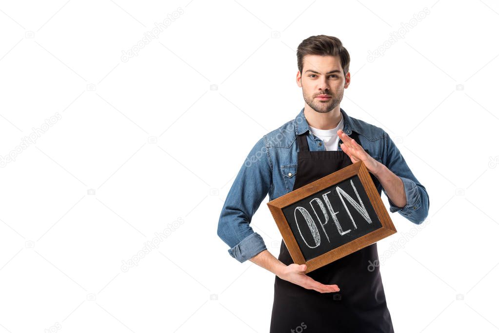 portrait of young waiter in apron with open blackboard isolated on white
