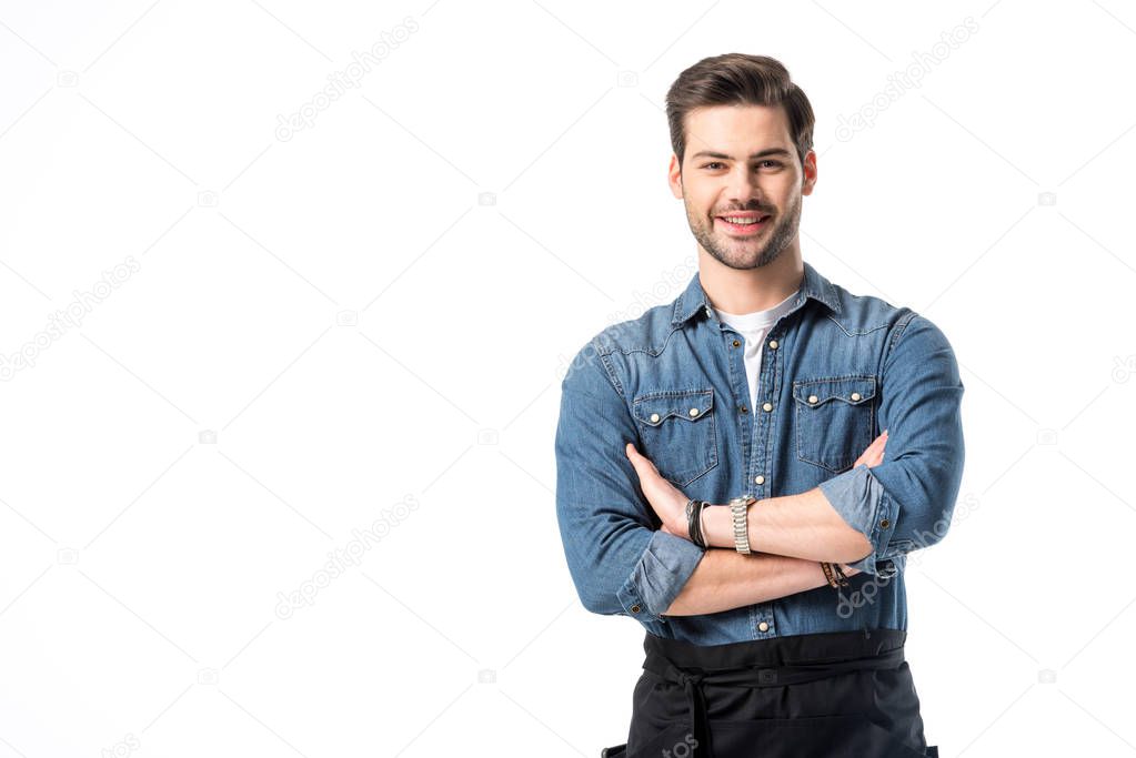 portrait of smiling waiter in apron with arms crossed isolated on white