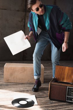 handsome young man in vintage windcheater with vinyl record player clipart