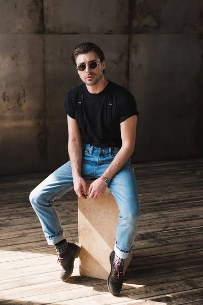 Przystojny Młody Człowiek Czarny Shirt Szelki Siedząc Drewniane Pudełko — Zdjęcie stockowe