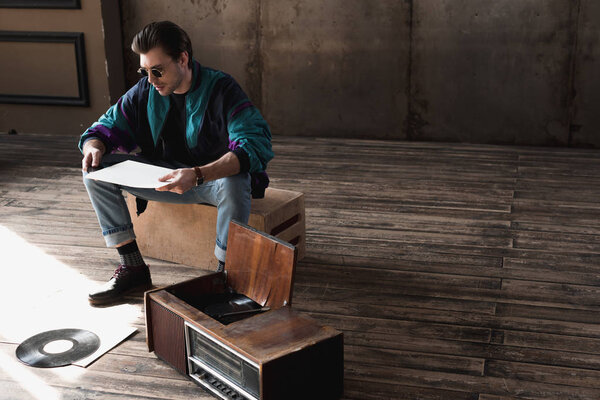 thoughtful nostalgic man in vintage windcheater with vinyl record player