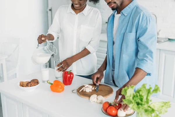 Vista Parcial Mujer Afroamericana Vertiendo Leche Vaso Mientras Marido Cocina — Foto de Stock