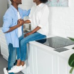 Vista parcial de pareja afroamericana cogida de la mano en la cocina en casa