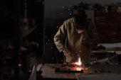 pracovník v ochranné masce svařování kovů v továrně 