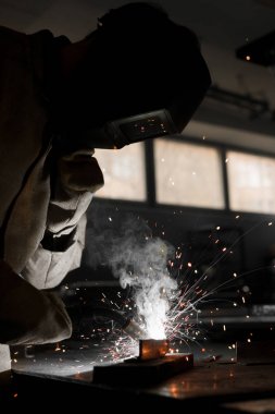 welder in protection mask working with metal at factory  clipart