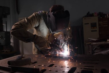 worker in protection mask welding metal at factory  clipart