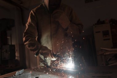 cropped image of worker in protection mask welding metal at factory  clipart