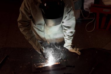 high angle view of worker in protection mask welding metal at factory  clipart