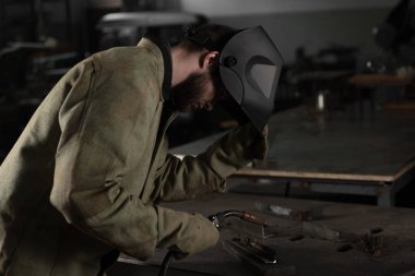 eserleri Fabrikası'nda bakmak için Kaynakçı koruyucu maske kaldırma