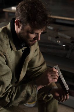 oturma ve metal parça Fabrikası'nda bakarak genç erkek işçinin yüksek açılı görünüş