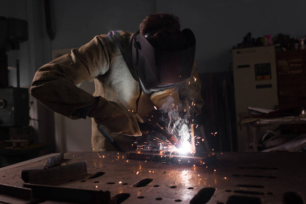  worker in protection mask welding metal at factory 