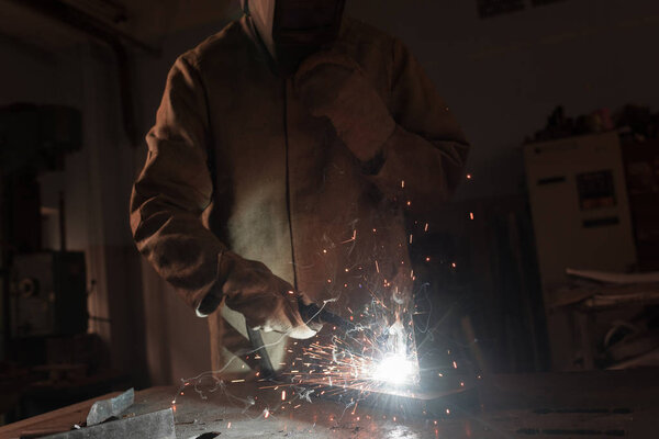 cropped image of worker in protection mask welding metal at factory 