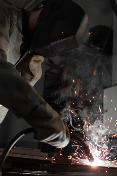 manufacture worker welding metal with sparks at factory 