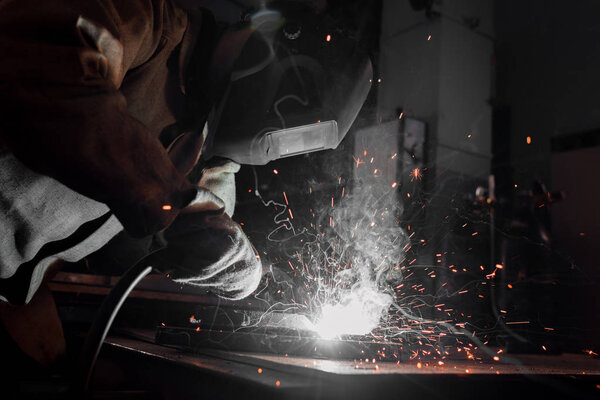 side view of worker in protection mask welding metal at factory 