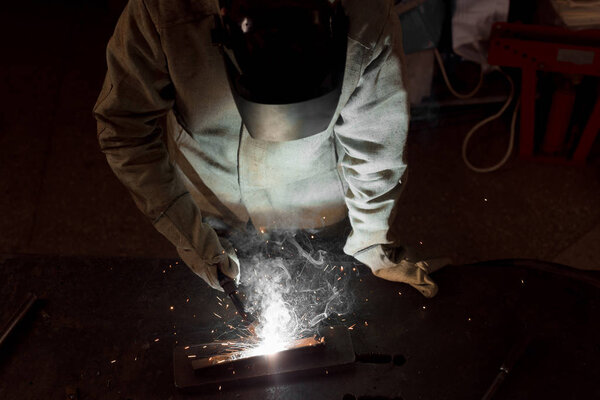 high angle view of worker in protection mask welding metal at factory 