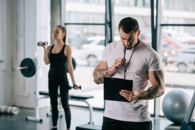 erkek kişisel antrenör Pano ve genç sporcumuz spor salonunda dumbbells ile egzersiz ile