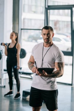 Pano ve genç sporcumuz spor salonunda dumbbells ile egzersiz ile kişisel antrenör