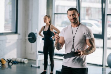 spor salonunda dumbbells ile egzersiz jest ve genç sporcumuz yukarı yapıyor pano ile kişisel antrenör