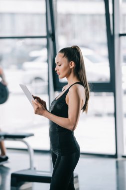 kadın kişisel antrenör dijital tablet vasıl jimnastik salonu ile yan görünüm 