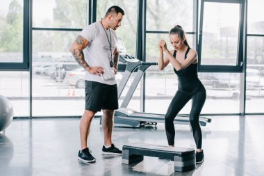 genç atletik kadının adım aerobik egzersiz ve spor salonunda erkek kişisel antrenör yapması