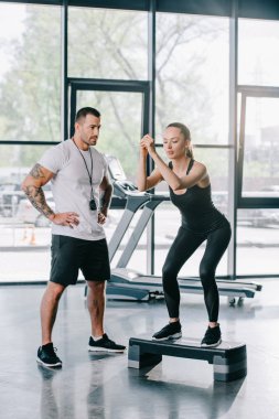 spor salonunda egzersiz erkek kişisel antrenör ve genç sporcumuz step aerobik yapıyor
