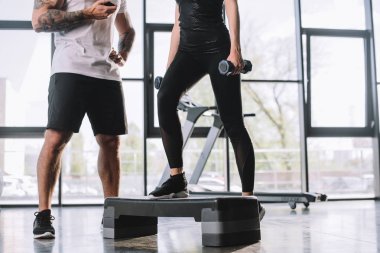 erkek kişisel eğitmen ile zaman ve genç sporcumuz adım aerobik egzersiz spor salonunda dumbbells ile yaparak kırpılmış atış
