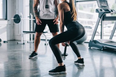 sporcumuz dumbbell ve yakındaki spor salonunda duran erkek kişisel antrenör ile yapıyor