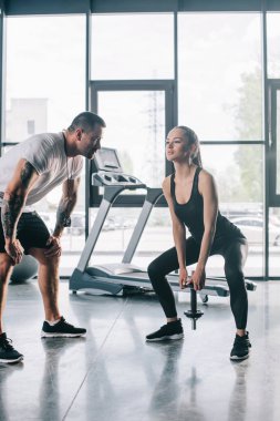 erkek kişisel antrenör ile Halter salonunda egzersizleri yapıyor sporcumuz bakarak