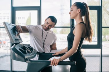 erkek kişisel antrenör koşu bandı ekran ve yakındaki spor salonunda duran sporcumuz işaret 