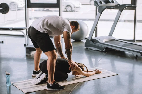 Entrenador Personal Masculino Ayudando Joven Atlética Estirarse Estera Fitness Gimnasio —  Fotos de Stock