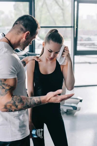 Maschio Personal Trainer Tirando Giovane Sportiva Con Bottiglia Acqua Pulire — Foto stock gratuita