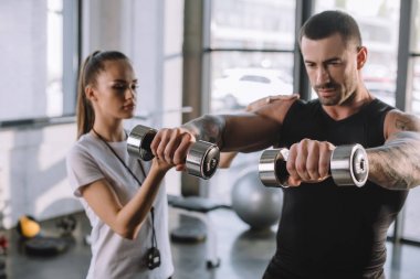kadın kişisel antrenör sporcu spor salonunda dumbbells ile egzersizleri yapmak için yardım