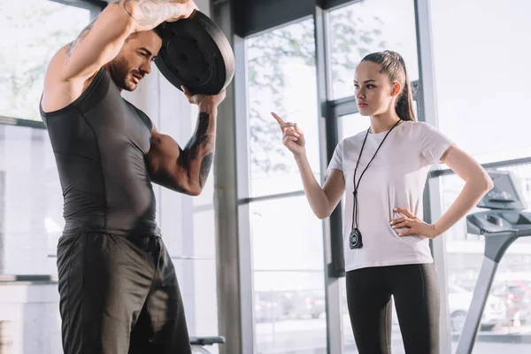 Personaltrainerin Zählt Während Sportler Fitnessstudio Übungen Mit Der Langhantelscheibe Machen — Stockfoto