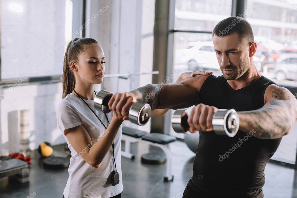 Entrenadora Personal Femenina Ayudando A Deportista A Hacer Ejercicios Con Pesas En El Gimnasio 2022