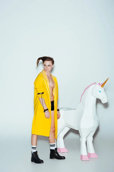 Stylish Man Hairstyle Yellow Raincoat Standing Big Unicorn Toy Grey — Stock Photo, Image