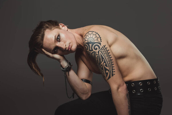 shirtless man with tattoo and strange hairstyle, isolated on grey