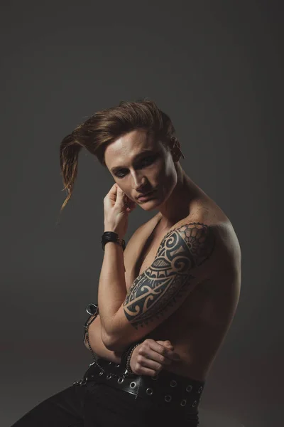 shirtless man with strange hairstyle and tattoo on hand, isolated on grey