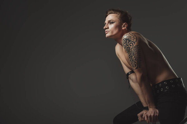 handsome tattooed shirtless man posing for fashion shoot, isolated on grey