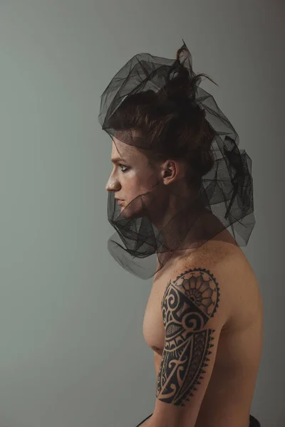 shirtless tattooed man with fashionable black net on head, isolated on grey