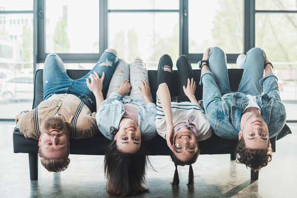 Улыбающиеся деловые люди, валяющиеся на диване в современном светлом офисе
