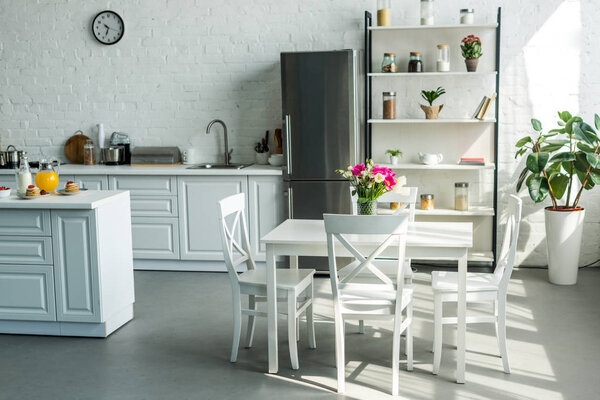 интерьер современной светлой кухни со столом и стульями

