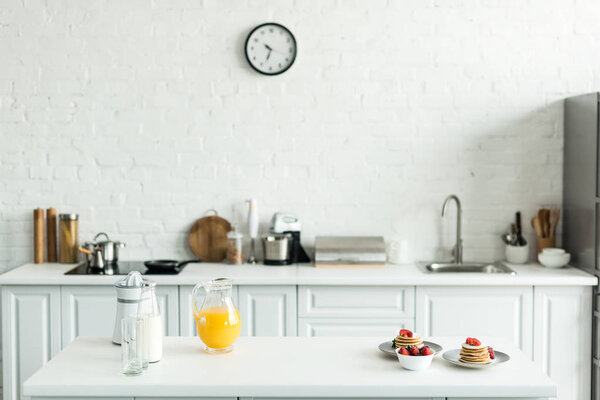 interior of kitchen with yummy pancakes and orange juice on kitchen counter