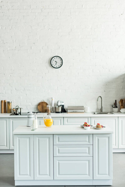 interior of modern light kitchen with pancakes and orange juice on kitchen counter