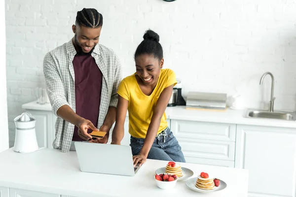 Smiling African American Couple Shopping Online Credit Card Laptop Kitchen — Stock Photo, Image