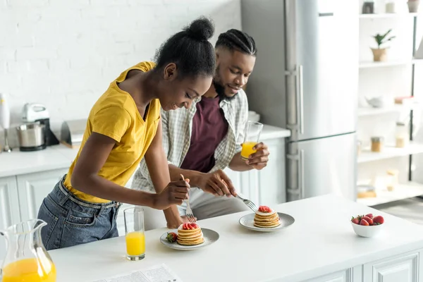 アフリカ系アメリカ人カップルのパンケーキを食べるとキッチンでオレンジ ジュースを飲む — ストック写真