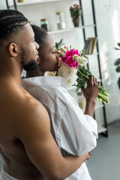 非洲裔美国男友拥抱女友 她在厨房嗅花香 — 免费的图库照片